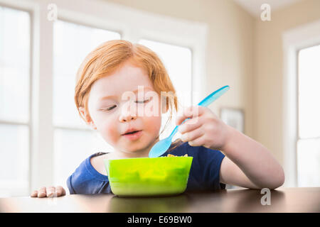 Caucasian girl eating at table Banque D'Images