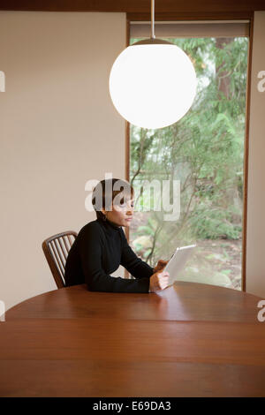 Caucasian woman using tablet computer at table Banque D'Images