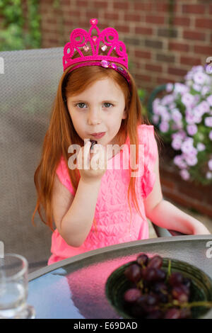 Caucasian girl eating fruit in backyard Banque D'Images