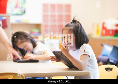 Mixed Race Down syndrome student using tablet computer in classroom Banque D'Images