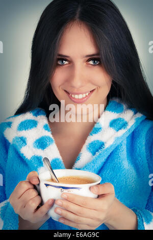 Jeune femme en peignoir avec une grande tasse de café Banque D'Images