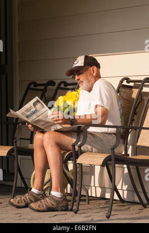 Homme mature sur terrasse arrière de sa maison lire les journaux du matin , USA Banque D'Images