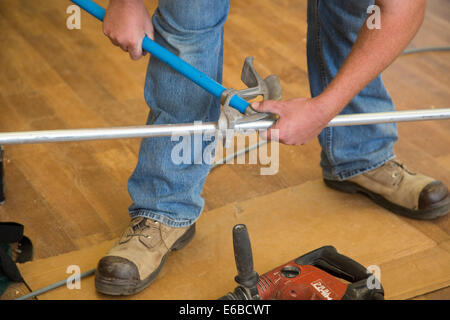 Detroit, Michigan - Un électricien bends volontaires conduit, comme la rénovation de la classe de l'économie domestique à Cody High School. Banque D'Images