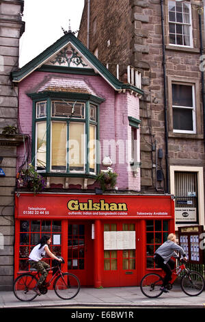 Deux femmes cyclistes équitation passé un restaurant indien de Gulshan le long de la Nethergate à Dundee, Royaume-Uni Banque D'Images