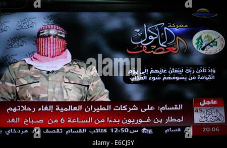 La ville de Gaza, bande de Gaza, territoire palestinien. 20e Août, 2014. Abu Ubaida, le porte-parole des brigades Izz el-Deen al-Qassam Brigade, l'aile armée du Hamas, est représenté sur un écran de télévision qu'il offre une déclaration télévisée sur la télévision du Hamas à Gaza, le 20 août 2014. L'aile militaire du Hamas, a déclaré mercredi une frappe aérienne israélienne à Gaza n'avait pas réussi à tuer son commandant militaire, Mohammed Deif. Dans une déclaration télévisée, Ubaida dit Israël avait manqué sa cible. L'épouse de Deif et fils de 7 mois ont été tués dans l'attaque d'Ashraf Amra Crédit : Images/APA/ZUMA/Alamy Fil Live News Banque D'Images