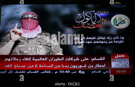 La ville de Gaza, bande de Gaza, territoire palestinien. 20e Août, 2014. Abu Ubaida, le porte-parole des brigades Izz el-Deen al-Qassam Brigade, l'aile armée du Hamas, est représenté sur un écran de télévision qu'il offre une déclaration télévisée sur la télévision du Hamas à Gaza, le 20 août 2014. L'aile militaire du Hamas, a déclaré mercredi une frappe aérienne israélienne à Gaza n'avait pas réussi à tuer son commandant militaire, Mohammed Deif. Dans une déclaration télévisée, Ubaida dit Israël avait manqué sa cible. L'épouse de Deif et fils de 7 mois ont été tués dans l'attaque d'Ashraf Amra Crédit : Images/APA/ZUMA/Alamy Fil Live News Banque D'Images