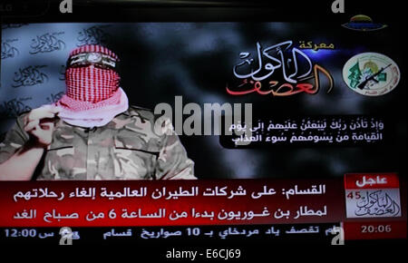 La ville de Gaza, bande de Gaza, territoire palestinien. 20e Août, 2014. Abu Ubaida, le porte-parole des brigades Izz el-Deen al-Qassam Brigade, l'aile armée du Hamas, est représenté sur un écran de télévision qu'il offre une déclaration télévisée sur la télévision du Hamas à Gaza, le 20 août 2014. L'aile militaire du Hamas, a déclaré mercredi une frappe aérienne israélienne à Gaza n'avait pas réussi à tuer son commandant militaire, Mohammed Deif. Dans une déclaration télévisée, Ubaida dit Israël avait manqué sa cible. L'épouse de Deif et fils de 7 mois ont été tués dans l'attaque d'Ashraf Amra Crédit : Images/APA/ZUMA/Alamy Fil Live News Banque D'Images