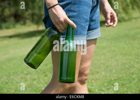 Woman's hand holding empty wine et les bouteilles de bière d'être recyclé Banque D'Images