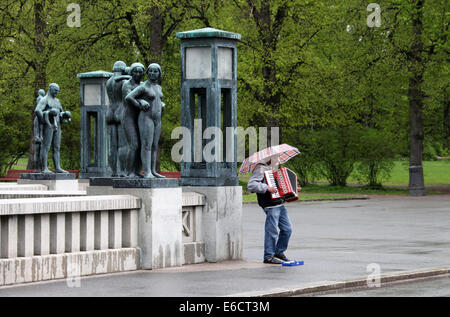 Joueur d'accordéon au Parc des sculptures de Vigeland à Oslo un jour de pluie Banque D'Images