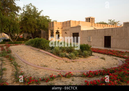 Jardin avec fleurs rouge vif, plantes grasses et d'arbres d'ombrage et l'extérieur de l'Arabe restaurant en vieille ville de secteur à Dubaï ÉMIRATS ARABES UNIS Banque D'Images