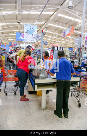 Couple mexicain de discuter du projet de loi avec supermarché hôtesse en uniforme comme les packs de sexe masculin dans des sacs articles Oaxaca Mexique Banque D'Images