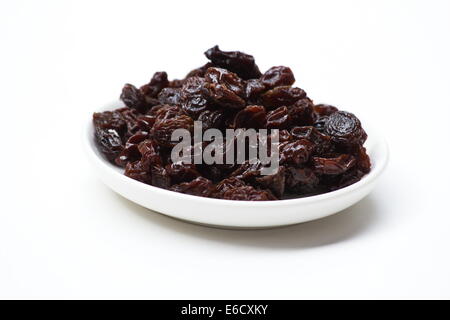 Les raisins secs dans un plat blanc sur fond blanc Banque D'Images