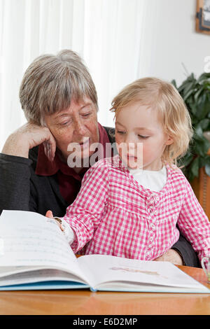 Grand-mère de la lecture d'un livre à sa petite-fille, 3 ans Banque D'Images