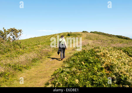 Une femme marchant sur la colline du château sur Mottistone commun sur l'île de Wight. Banque D'Images