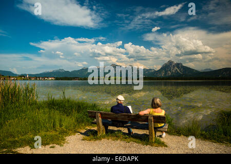 L'Allemagne, la Bavière, l'Allgaeu, Allgaeu, le lac Hopfensee, près de Füssen, vieux couple sur le banc en bois Banque D'Images