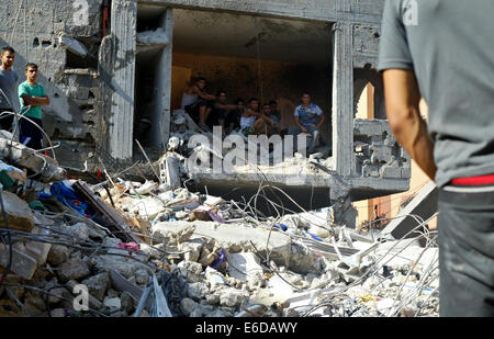 La bande de Gaza. 21e Août, 2014. Les Palestiniens se rassemblent autour de l'édifice détruit un de rocailles, après le Hamas affirme que trois de ses officiers supérieurs qui ont été identifiés comme Mohammed Abu Shamaleh, Raed Attar et Mohammed Barhoum qui ont été tués par des frappes aériennes israéliennes à Tel es-Sultan près de Rafah. Credit : Ibrahim Khatib/Pacific Press/Alamy Live News Banque D'Images