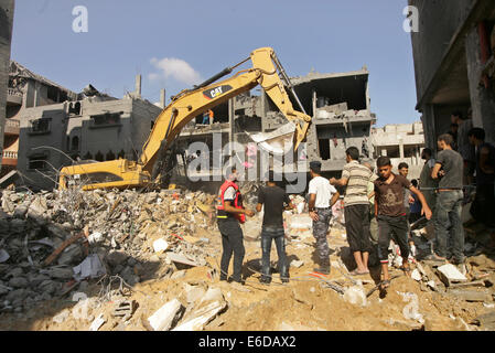 La bande de Gaza. 21e Août, 2014. Les Palestiniens se rassemblent autour de l'édifice détruit un de rocailles, après le Hamas affirme que trois de ses officiers supérieurs qui ont été identifiés comme Mohammed Abu Shamaleh, Raed Attar et Mohammed Barhoum qui ont été tués par des frappes aériennes israéliennes à Tel es-Sultan près de Rafah. Credit : Ibrahim Khatib/Pacific Press/Alamy Live News Banque D'Images