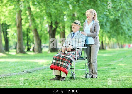 Hauts en fauteuil roulant assis dans un parc avec son épouse sur un jour d'été ensoleillé Banque D'Images