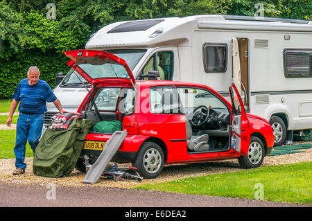 Un vieux / vieille / senior man packing sa voiture remorquage, lire pour laisser un camping Caravan Club en Angleterre, Royaume-Uni. Banque D'Images