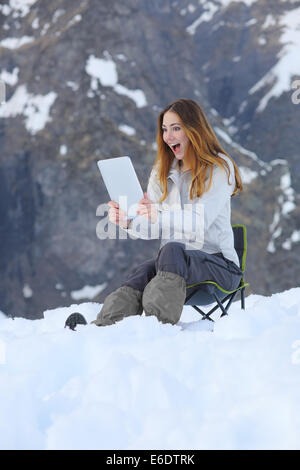 Surpris wow woman une tablette application dans une montagne enneigée en vacances Banque D'Images