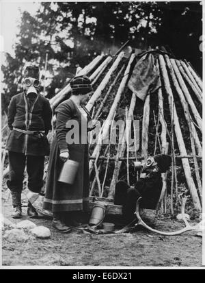 Famille Lapp portant des masques à gaz autorisés pour la protection de l'air en face de leur habitation primitive en préparation de la guerre, de la Suède, Banque D'Images