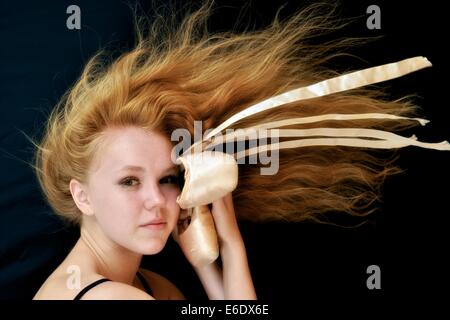 Portrait d'une jeune adolescente ballerina holding sa pointe chaussures de ballet. Banque D'Images