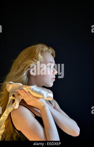 Portrait d'une jeune adolescente ballerina holding sa pointe chaussures de ballet. Banque D'Images