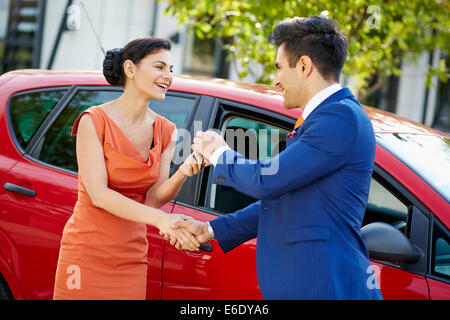 Vendeur de donner des clés sur une nouvelle voiture de womans attrayant Banque D'Images