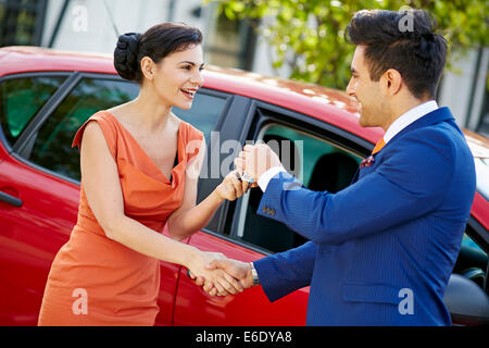 Vendeur de donner des clés sur une nouvelle voiture de womans attrayant Banque D'Images