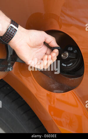 Main d'homme déverrouillant un bouchon de carburant antivol avec clé dans une station-service Banque D'Images