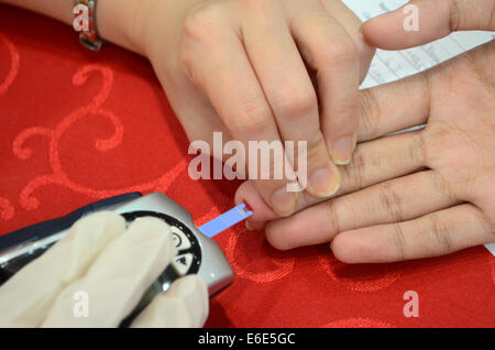 Close-up de sang du patient sur le doigt absorber sur bandelette de test Banque D'Images