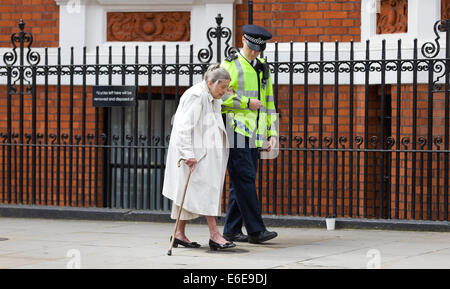 Royaume-uni, Londres : un agent de police contribue à une femme âgée comme elle marche dans le sentier menant au centre de Londres. 18.08.14. Banque D'Images