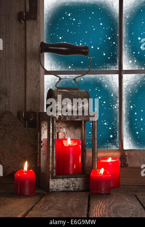 Décoration de Noël traditionnel en rouge : quatre brûler des bougies décorées sur la fenêtre avec une vieille lanterne d'étain. Banque D'Images