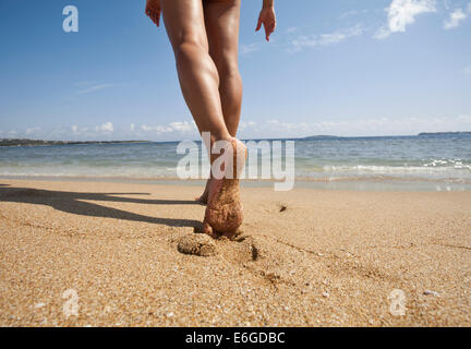 Jeune femme marcher seule sur la plage de sable. Closeup détail des pieds féminins et de sable doré. Banque D'Images
