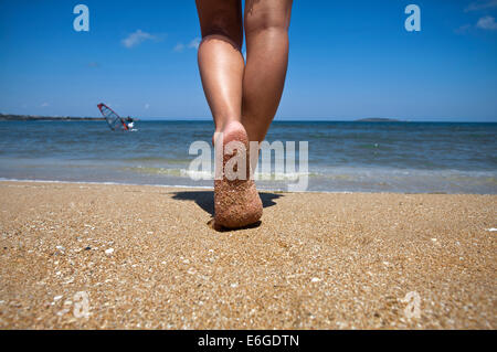 Jeune femme marcher seule sur la plage de sable. Closeup détail des pieds féminins et de sable doré. Banque D'Images