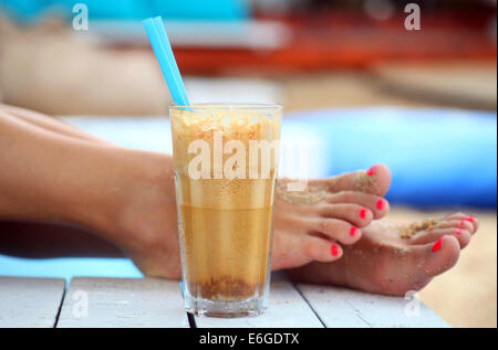 Café glacé et les pieds dans une plage exotique. Banque D'Images