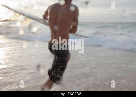 Surfer en marche dans l'eau à Sandy Beach Banque D'Images