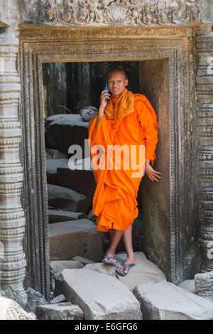 Moine cambodgien sur téléphone cellulaire à Ta Prohm temple à Angkor Banque D'Images