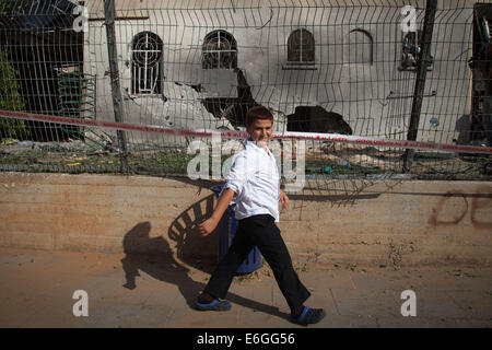 Frontière de Gaza, ville israélienne à la frontière de Gaza. 22 août, 2014. Un enfant israélien passe devant une synagogue juive endommagé frappée par une roquette lancée de la bande de Gaza à Ashdod, ville israélienne du sud en bordure de Gaza, le 22 août 2014. Un garçon de 4 ans a été tué vendredi soir par un tir de mortier sur le sud d'Israël, Magen David Adom, la Croix-Rouge, dit de Xinhua. © Albert/JINI Sadikov/Xinhua/Alamy Live News Banque D'Images