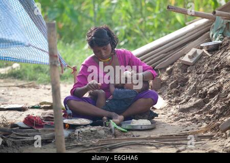 Bardiya, le Népal. 22 août, 2014. Une femme nourrit son enfant près de sa maison endommagée par des inondations en Bardiya, le Népal, le 22 août, 2014. Le nombre de victimes des inondations dans le nord de l'état indien de l'Uttar Pradesh au cours de la semaine dernière a augmenté pour atteindre près de 90, comme l'inondation est restée vive le jeudi, a déclaré que les fonctionnaires. © Pratap Thapa/Xinhua/Alamy Live News Banque D'Images