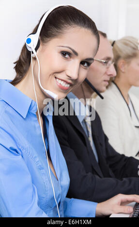 Happy business woman sur le téléphone dans un centre d'appel portant chemisier bleu. Banque D'Images