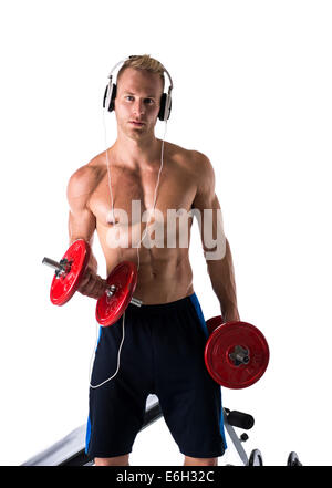 Portrait d'un jeune homme blond musclé soulevant des poids et d'écouter de la musique dans les écouteurs, isolé sur fond blanc Banque D'Images