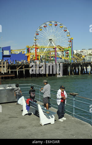 Deux adultes et deux enfants pêche à la jetée de Santa Monica, d'attractions Pacific Park juste en arrière-plan. Santa Monica, Californie Banque D'Images