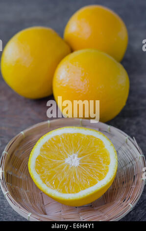 Fruits d'orange et la moitié dans panier sur fond de bois Banque D'Images