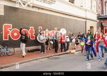 Les touristes passent devant le brass band joue de la musique pour des conseils sur Bourbon Street dans le quartier français de La Nouvelle-Orléans Banque D'Images