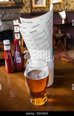 Une pinte de bière en face de menus de déjeuner dans un pub anglais traditionnel Banque D'Images
