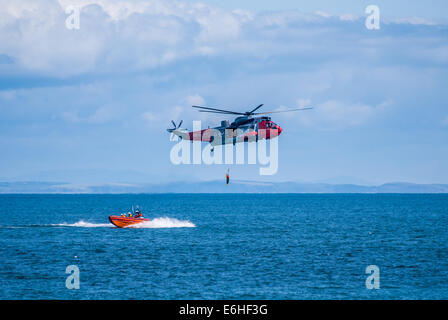 Millisle, Newtownards, comté de Down, Irlande du Nord, Royaume-Uni. 24 août 2014. Hélicoptère de sauvetage de la Marine royale de treuillage pratiquant avec des dirigeables de la RNLI. Hélicoptère de sauvetage de la Marine royale et les membres de la RNLI. Exercice d'entraînement. Crédit : Jeffrey silvers/Alamy Live News Banque D'Images