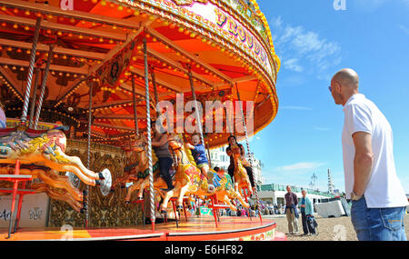 Les familles profitent des promenades sur le front de mer de Brighton carrousel dans la lumière du soleil chaude aujourd'hui Banque D'Images