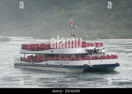 New York, Niagara. Bateau d'excursion panoramique bondé (Hornblower), du côté canadien, avec les touristes en rouge la pluie ponchos. Banque D'Images