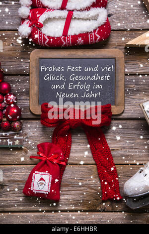 Carte de vœux joyeux Noël en rouge et blanc avec le bois et le texte allemand. Banque D'Images